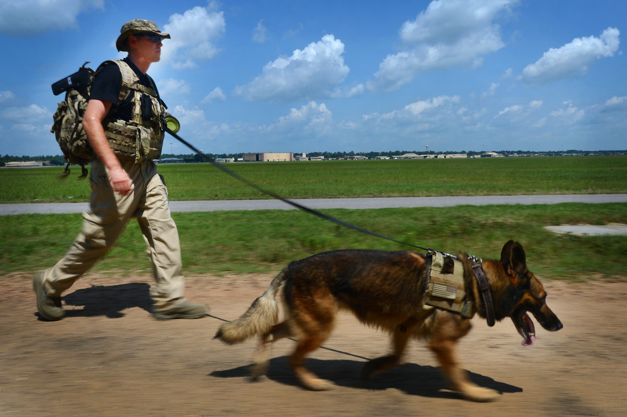 U.S. Air Force Senior Airman Robert Coughlin, 20th Security Forces Squadron military working dog handler, follows his K-9, Sati, down a path at Shaw Air Force Base, S.C., July 24, 2014. The two, who have been paired together for two months, walked more than five miles in 90 degree heat to acclimate the K-9 to the long missions and high temperatures typical of a deployed environment. (U.S. Air Force photo by Airman 1st Class Jensen Stidham/Released) 