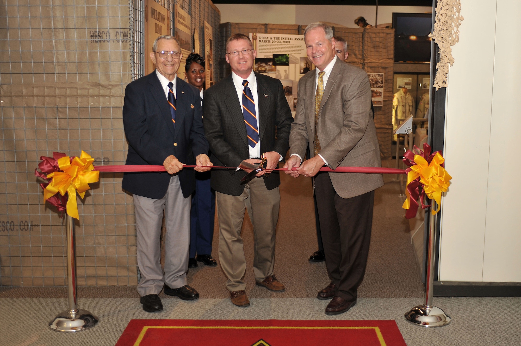 From left, retired U.S. Army Col. James Rockey, Army Transportation Museum Foundation president, David Hanselman, museum director, and retired Brig. Gen. James Hodge, guest speaker, cut the ceremonial ribbon during the museum’s Operations Iraqi and Enduring Freedom exhibit opening at Fort Eustis, Va., July 24, 2014. Following the ribbon-cutting, the museum also held a Hall of Fame induction ceremony to honor 10 people who made significant contributions through actions beyond normal duty which enhanced the Transportation Corps’ mission. (U.S. Air Force photo by Staff Sgt. Katie Gar Ward/Released)