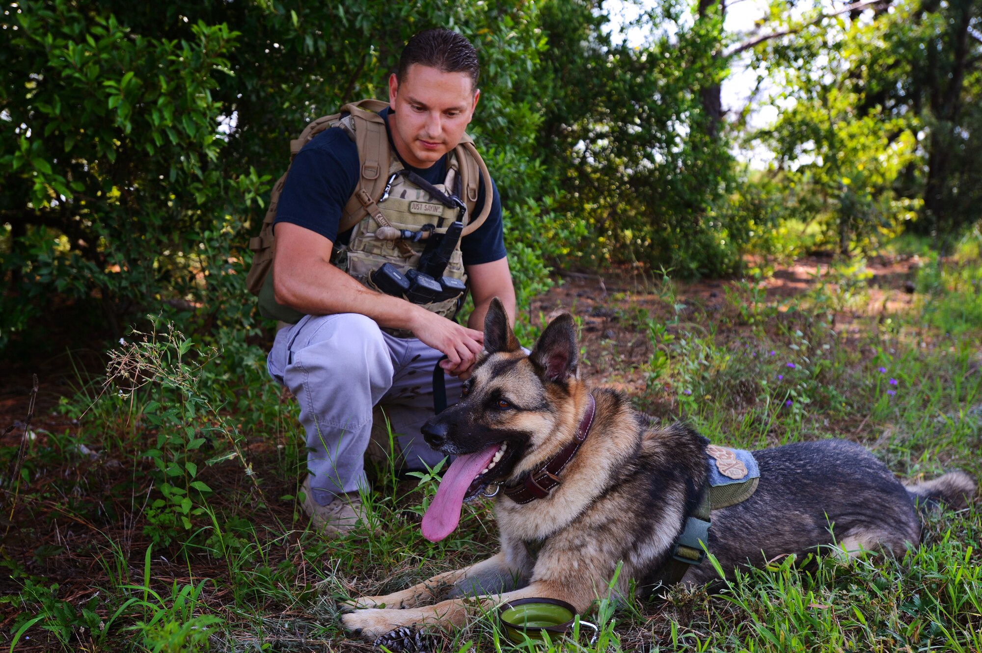 U.S. Air Force Staff Sgt. David Mussio, 20th Security Forces Squadron military working dog trainer, and his K-9, Sati, sit in the shade at Shaw Air Force Base, S.C., July 24, 2014. Mussio and Sati were halfway through a five-mile training exercise meant to prepare both for high heat and long missions while deployed. (U.S. Air Force photo by Airman 1st Class Jensen Stidham/Released)