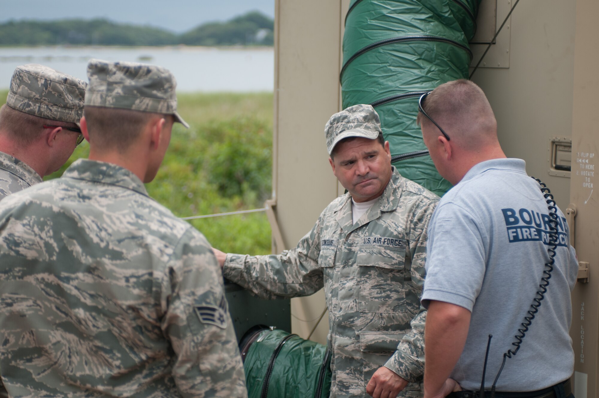 Tech. Sgt. Peter Vasconcellos explains the operation of an military air conditioning unit to Lt. Greg Edgcomb, of the Bourne Fire Department, July 24, 2014 on Mashnee Rd. in Bourne, Mass. The unit is part of an emergency medical station that will be manned by Bourne Fire Department members during the Pan-Mass Challenge, an annual bike-a-thon that supports the Dana-Farber Cancer Institute.(National Guard photo by Master Sgt. Aaron Smith/Released)