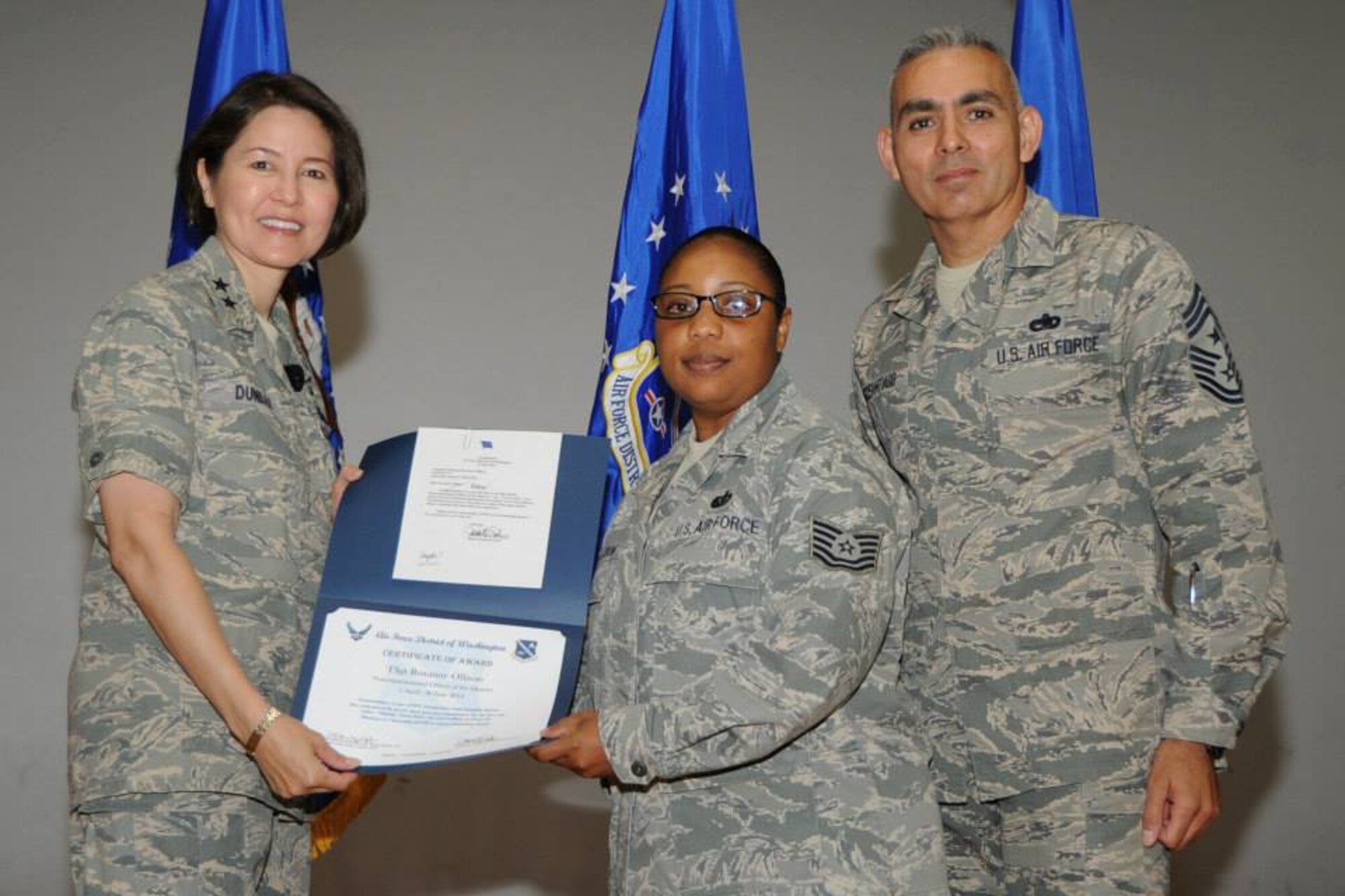 Air Force District of Washington Commander Maj. Gen. Sharon K. G. Dunbar and AFDW Command Chief Master Sgt. Jose LugoSantiago recognize Tech. Sgt. Roxanne Ollison as the NCO of the Quarter during AFDW Commander’s Call at Joint Base Andrews, Maryland, July 15, 2014. Ollison works in the AFDW Ceremonies and Protocol directorate. (U.S. Air Force photo/Staff Sgt. Matt Davis)