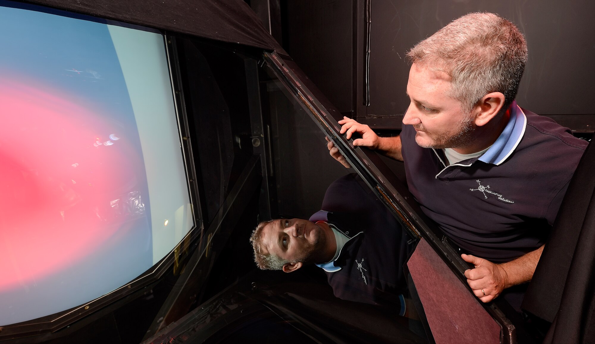 Johnny R. Johnson, an electronics technician for Nakuuruq Solution, performs a visual inspection of mirrors and lenses inside the C-5 Air Refueling Partial Task Trainer July 23, 2014, at Dover Air Force Base, Del. A series of mirrors and lenses project an image of a refueling tanker into a cockpit mock-up to allow pilots to practice air refueling procedures. (U.S. Air Force photo/Greg L. Davis)