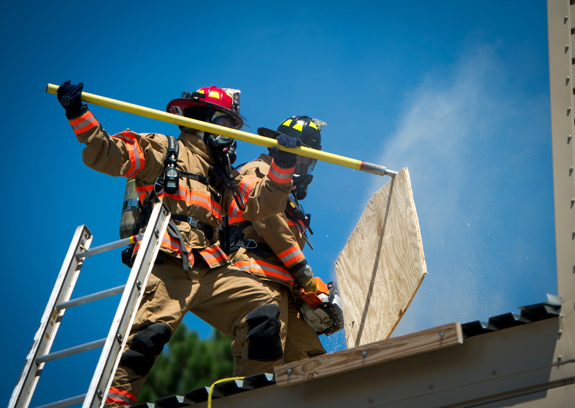 A Hurlburt Field firefighter removes a cut-out piece of wood on top of a roof during training on Hurlburt Field, Fla., July 17, 2014. The firefighters used a high-powered saw to cut the wood to help the smoke-filled building vent properly. (U.S. Air Force photo/Senior Airman Christopher Callaway) 
