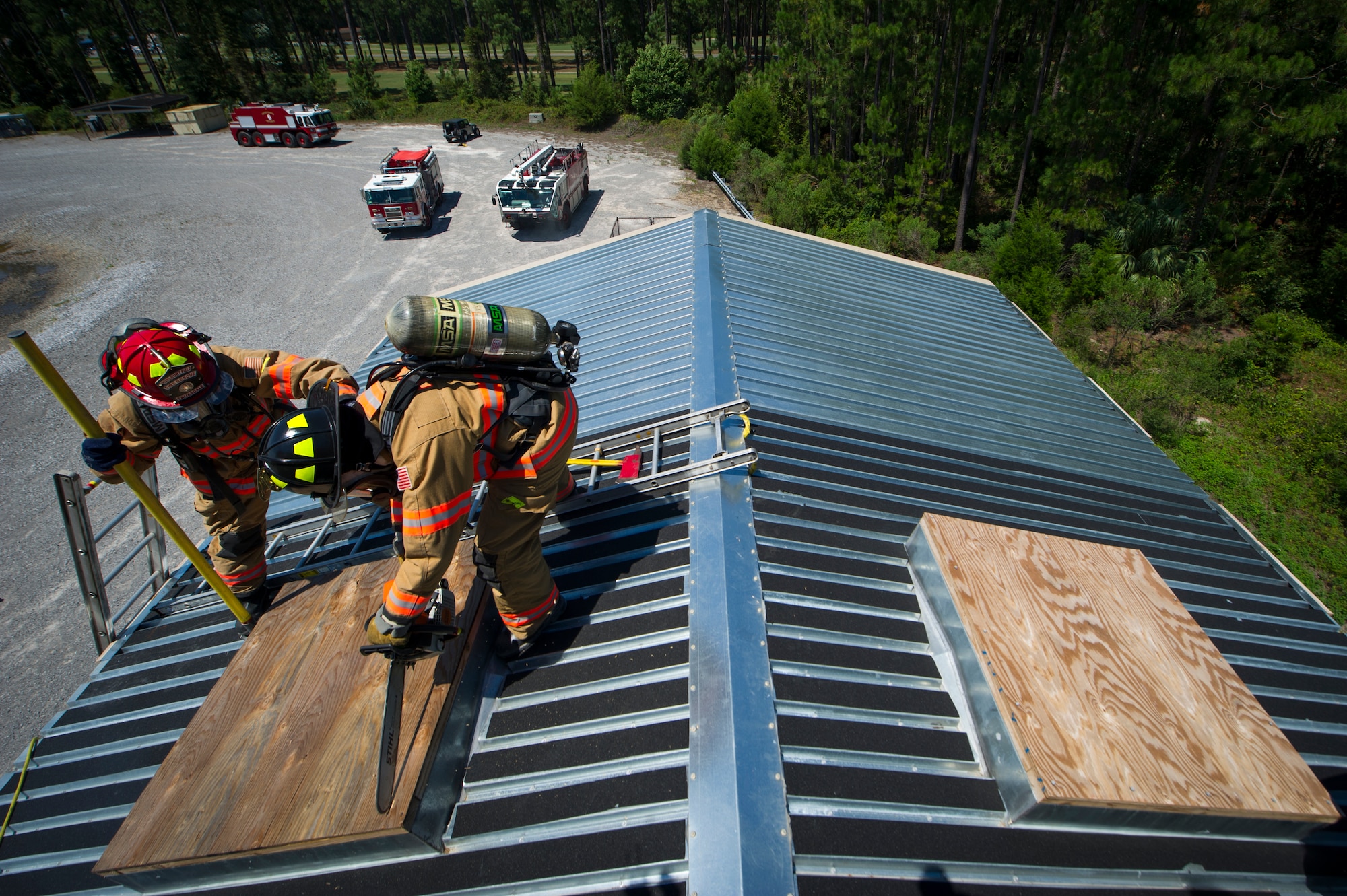 Two Hurlburt Field firefighters work together to penetrate the top of a roof during ventilation training on Hurlburt Field, Fla., July 17, 2014. The Airmen trained on top of a new three-story building that can simulate multiple emergency scenarios. (U.S. Air Force photo/Senior Airman Christopher Callaway) 