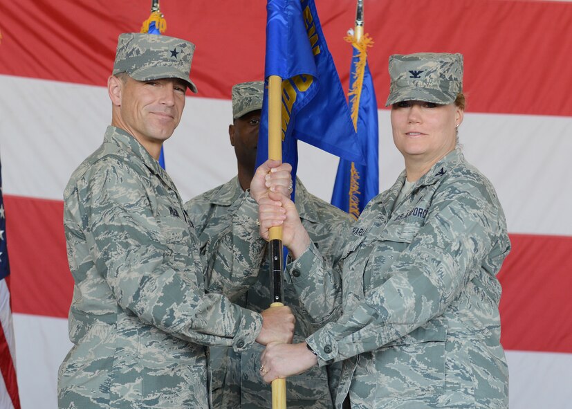 Brig. Gen. Scott Pleus, 56th Fighter Wing commander, passes the guidon to Col. Maureen Charles, incoming 56th Medical Group commander, during a change-of-command ceremony July 18 in Hanger 431 at Luke Air Force Base. (U.S. Air Force photo/Senior Airman Devante Williams)