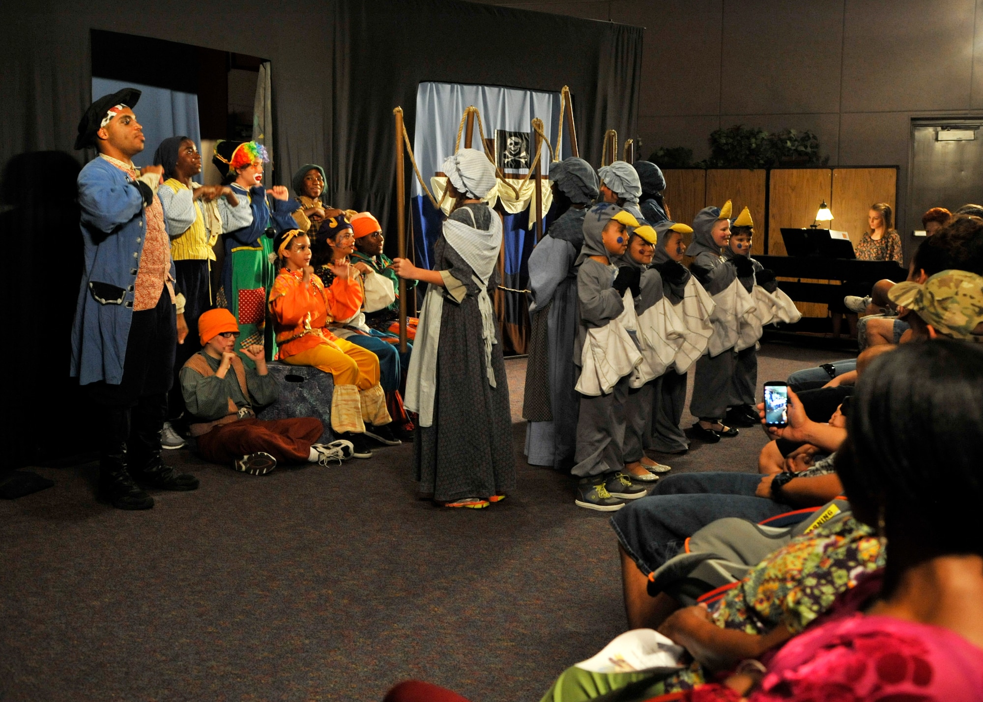 Long John Silver (Kwame Lilly), Cap’n Patches (Sonja Barajas), Davey the Letterman (Terrell Straton), Sing-Sing Sam (Emily Ray), Goldie the Hun (Hannah Hudgins), Mother Hawkins (Simone Commack), Hawkins sisters played by Helena Stratton (Janie), Cambrie Ellison (Joanie), Yvonne Walker (Jinnie) and Carly Cooper (Jan) and the Gulls played by Aiden Marsden, Kai Card, Alana Crudup, Jesse Rico, and Jillian Coddington sing during “Treasure Island” on Luke Air Force Base. (U.S. Air Force photo/Senior Airman Marcy Copeland)