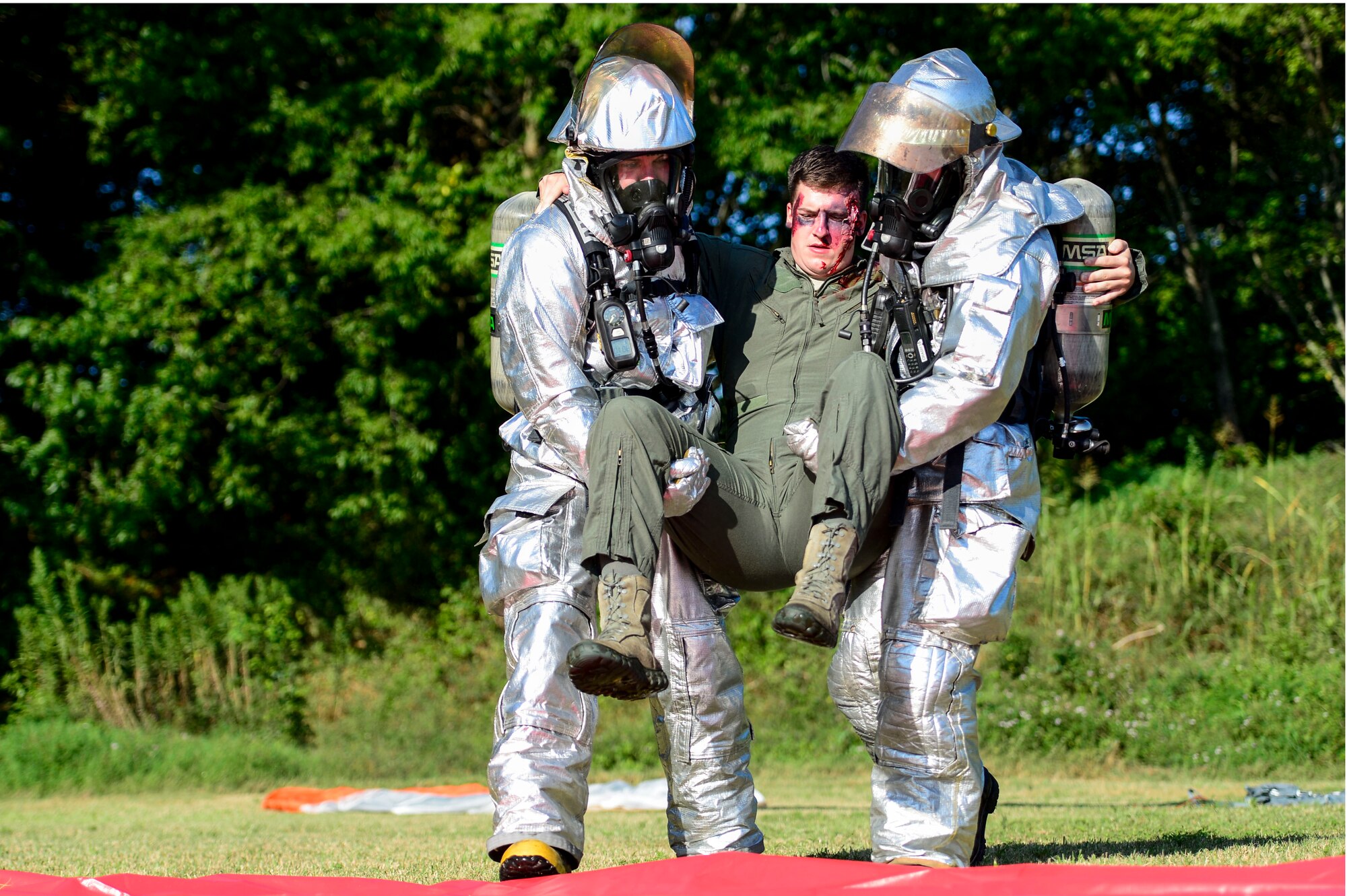Firefighters from the 633rd Civil Engineer Squadron carry a simulated downed pilot to safety during an exercise at Langley Air Force Base, Va., July 25, 2014. The exercise tested the ability of the City of Hampton and Langley initial and emergency responders to react to an F-22 Raptor and T-38 Talon aircraft crash. (U.S. Air Force photo by Senior Airman Kayla Newman/Released)  
