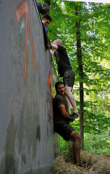 A Mudless Mudder team helps each other over an obstacle on June 19, 2014 at Ramstein Air Base, Germany. The obstacles consisted of a low-crawl, hay bales, a tightrope, a tire hill and dunk tanks, just to name a few. (U.S. Air Force photo/Airman Larissa Greatwood)