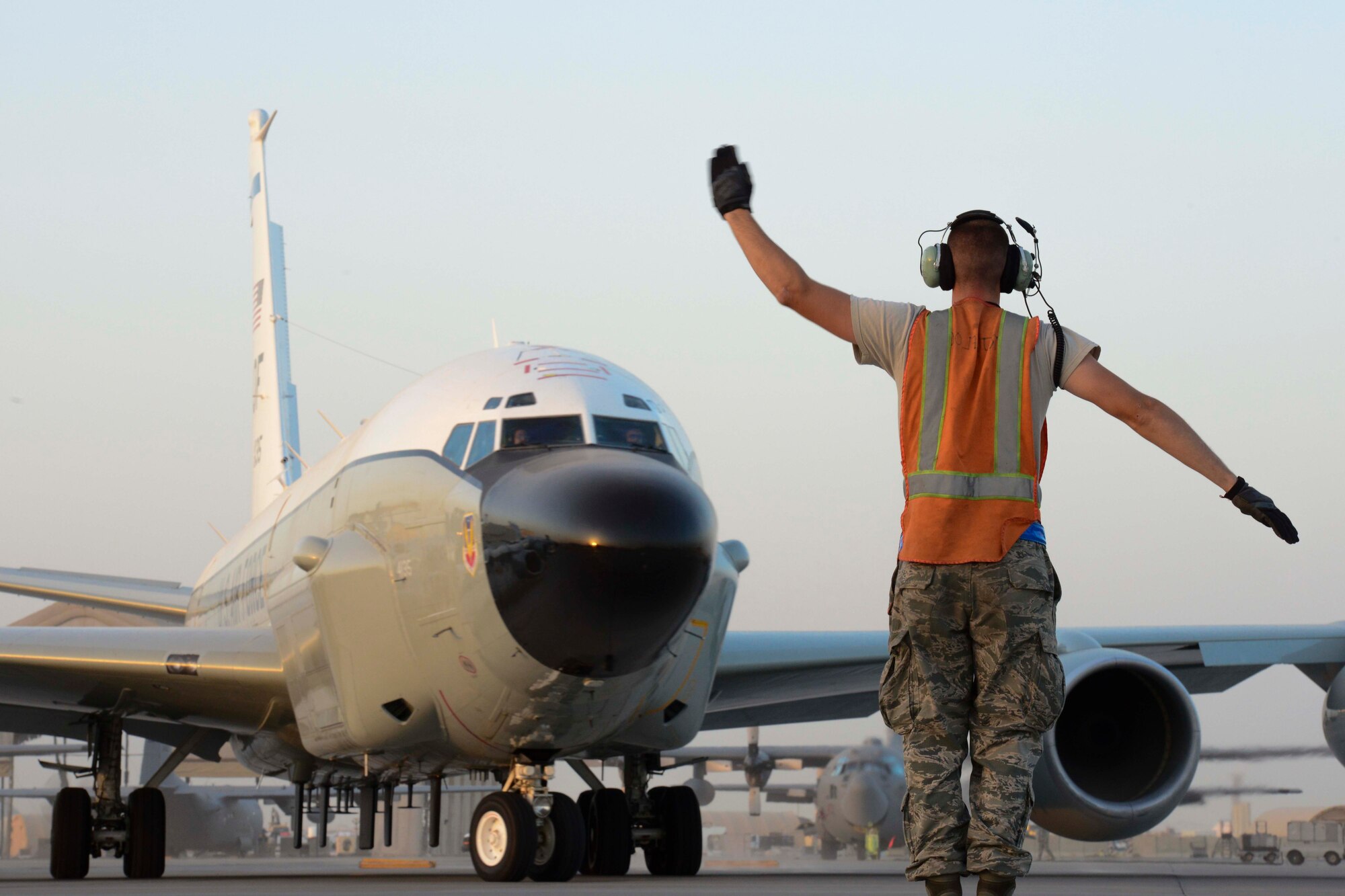U.S. Air Force Senior Airman Brandon Worra, 763rd Aircraft Maintenance Unit communications navigations specialist, directs a RC-135 Rivet Joint for taxiing for takeoff at Al Udeid Air Base, Qatar, July 11, 2014. The RC-135 Rivet Joint is a reconnaissance aircraft, and supports theater and national level consumers with near real-time on-scene intelligence collection, analysis and dissemination capabilities. Worra is deployed from Offut Air Force Base, Nebraska and hails from Muskegon, Michigan. (U.S. Air Force photo by Staff Sgt. Ciara Wymbs) 