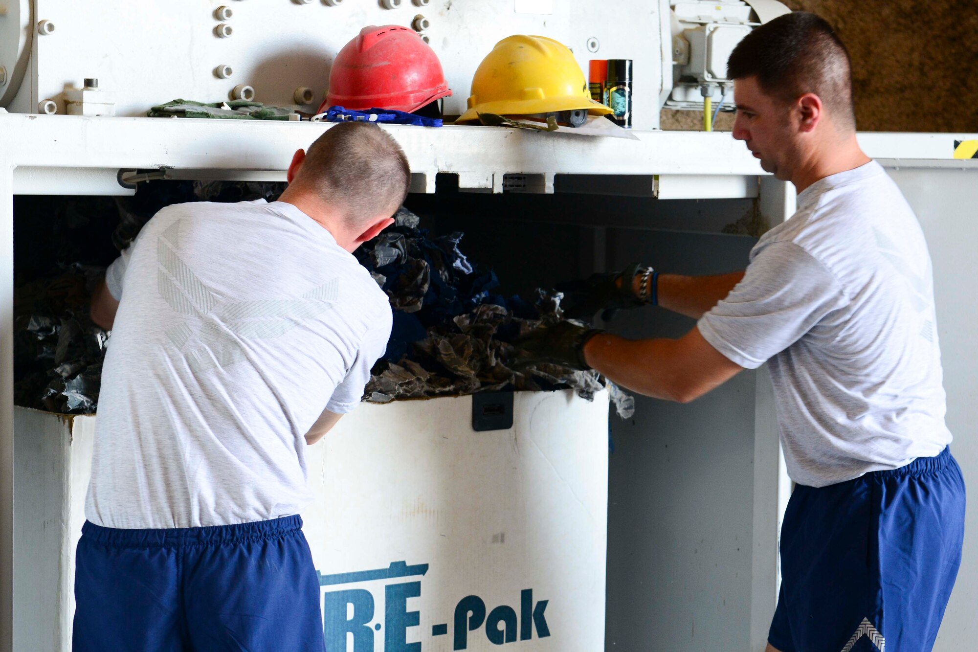 U.S. Air Force Tech. Sgt. Patrick Keenan, 379th Air Expeditionary Wing operations security program manager and Tech. Sgt. Christopher West, 379th  Expeditionary Security Forces Squadron antiterrorism office, remove shredded uniform items at Al Udeid Air Base, Qatar, July 24, 2014. The shredding is conducted on a weekly basis at the 379 th Expeditionary Communications Squadron Automated Data Processing Equipment building. Keenan is a Ischua, New York native, West is from Mansfield, Ohio. (U.S. Air Force photo by Staff Sgt. Ciara Wymbs) 