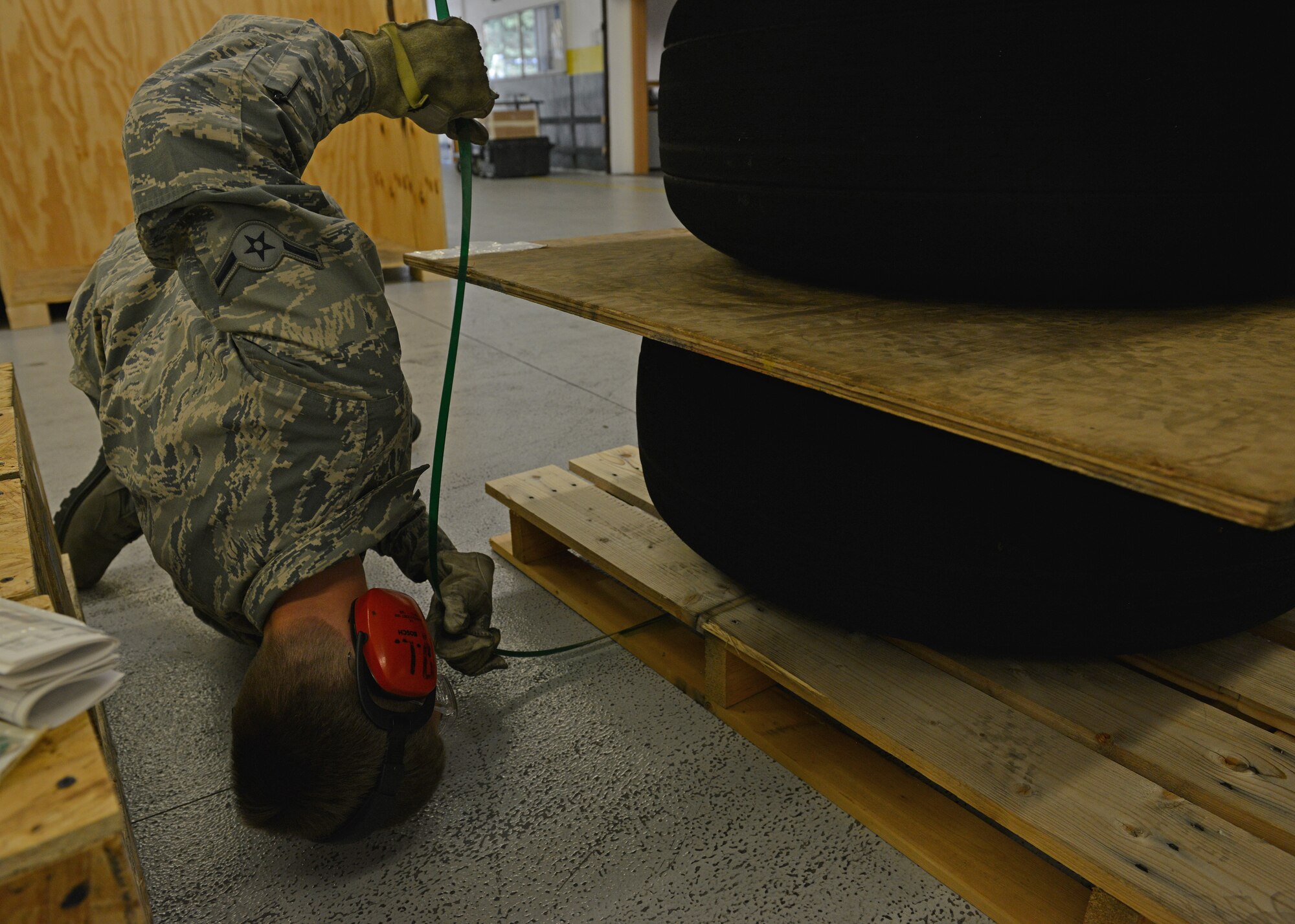 Airman Kyle Wild, 86th Logistics Readiness Squadron traffic management operations specialist, bands tires to prepare them for shipment July 23, 2014, Ramstein Air Base, Germany. The distribution division delivers equipment and other cargo to ensure Department of Defense missions are successful. (U.S. Air Force photo/Senior Airman Holly Mansfield)
