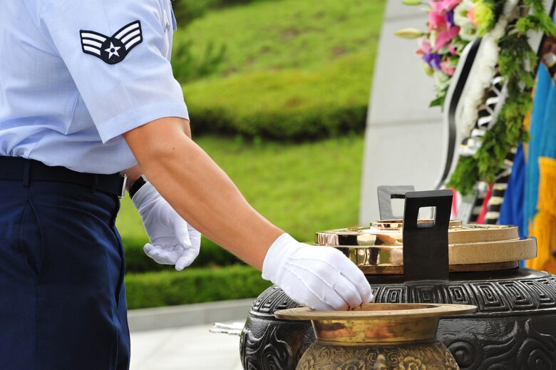 Senior Airman Jeff Dickson, 8th Civil Engineer Squadron firefighter, transfers incense to an urn with ceremonial gloves during the official proceedings of an Armistice Agreement anniversary ceremony at Imsil National Cemetery, Republic of Korea, July 22, 2014. The incense was burned in the accompanying urn in remembrance of the lives lost and the sacrifices made during the Korean War. (U.S. Air Force photo by 1st Lt. Earon Brown/Released)