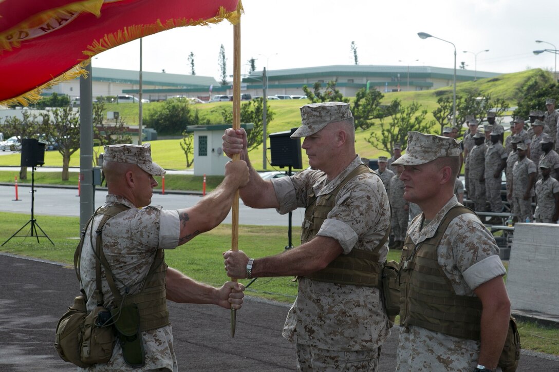Brig. Gen. Niel E. Nelson, center, receives the 3rd Marine Logistics Group colors from Sgt. Maj. Michael J. Hendges, left, during a change of command ceremony July 18 at Roberts Field on Camp Kinser. After receiving the colors, Nelson passed them to the incoming commanding general, Brig. Gen. (select) Tracy W. King. The “passing of the colors” symbolizes the transfer of command of 3rd MLG from Nelson to King. King is an Oklahoma City, Oklahoma, native, and Nelson is a Genoa, Nevada, native. Hendges is a South Carolina native and the 3rd MLG sergeant major. (U.S. Marine Corps photo by Lance Cpl. Pete Sanders/Released)