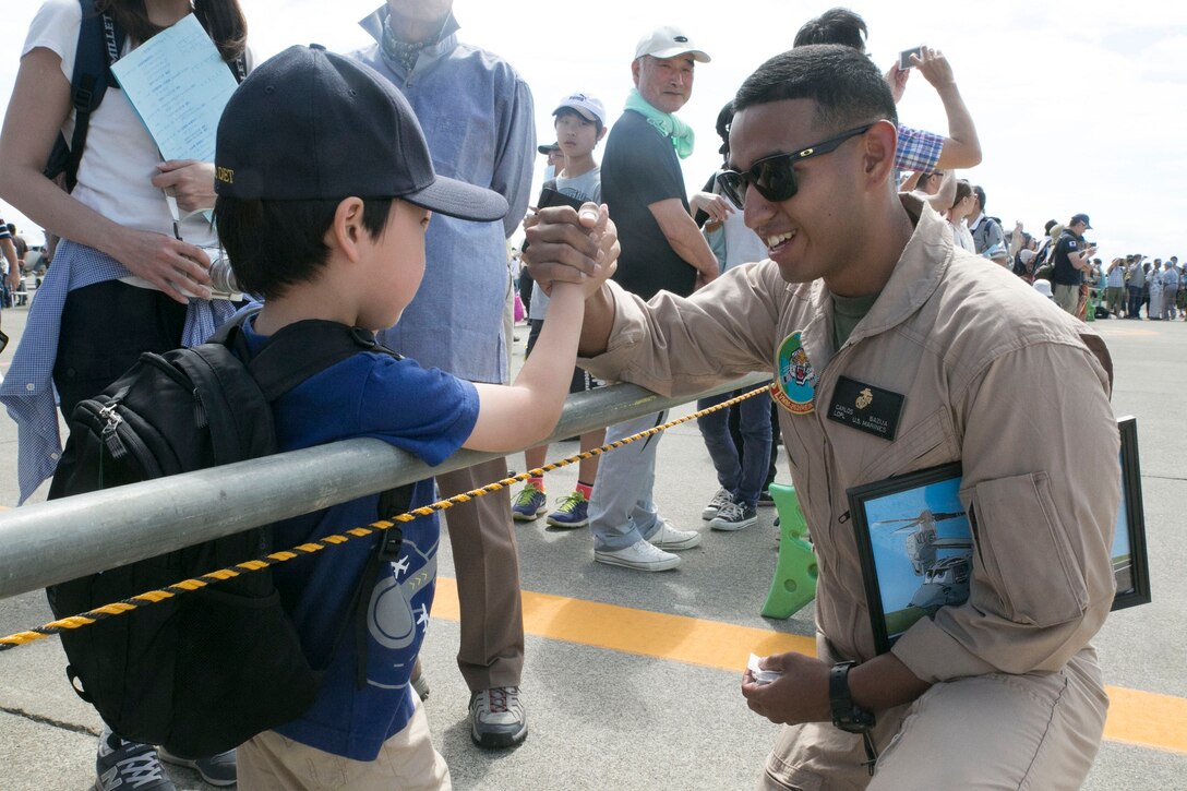 Lance Cpl. Carlos E. Bazuarojas, right, shakes hands with a Japanese child during the 28th Sapporo Airshow July 20 at the Sapporo Okadama Airport. With more than 20,000 people in attendance, the airshow experienced its largest audience to date. The Osprey made its debut at the airshow to familiarize the Japanese community with the aircraft and give them the chance to look inside. Bazuarojas is a Mesa, Arizona, native and flight equipment technician with Marine Medium Tiltrotor Squadron 262, Marine Aircraft Group 36, 1st Marine Aircraft Wing, III Marine Expeditionary Force. (U.S. Marine Corps Photo by Lance Cpl. Thor J. Larson/ Released) 