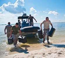 Members from the Joint Communications Support Element unload gear from the boat that transported them to a simulated remote island near MacDill Air Force Base, Fla., to conduct an exercise July 23, 2014. The exercise tested the unit's readiness for rapid deployment communications operations.