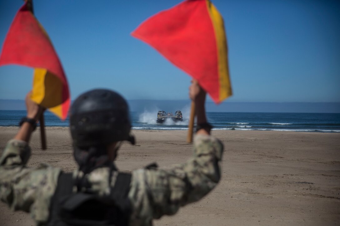 A Navy Landing Craft, Air Cushion approaches the beach carrying a M1 Abrams tank with Company E, 4th Tank Battalion, 4th Marine Division, Marine Forces Reserve, as a sailor directs them in during a simulated ship-to-shore movement as a part of the battalion’s annual training exercise here, July 21, 2014. The two week exercise included live-fire tank and infantry integration as well as amphibious operations which gave the Marines a chance to operate in a simulated ship-to-shore movement. (U.S. Marine Corps photo by Cpl. Codey Underwood)