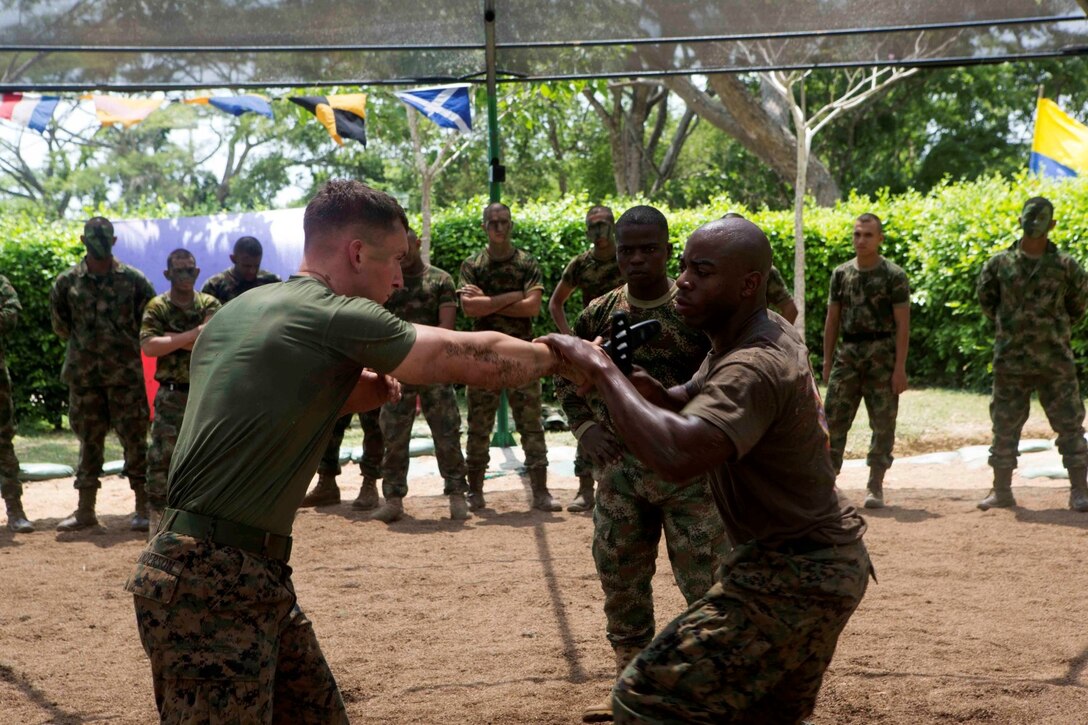 Sergeant Tyson Hicks, right, a martial arts instructor trainer with Special Purpose Marine Air Ground Task Force South, and a native of Lynwood, Calif., and Lance Cpl. Kyle Anderson, a team leader with SPMAGTF-South, and a native of Easley, S.C., demonstrate techniques from the Marine Corps Martial Arts Program for Colombian Marines during a martial arts training exchange at Colombian Marine Corps Base Coveñas, Colombia, July 16, 2014. The SPMAGTF came to Colombia aboard the future amphibious assault ship USS America (LHA 6) during its transit around South America. A SPMAGTF is a balanced air, ground and logistics force that can be tailored to accomplish missions across a wide range of crises. As the first stop on the ship's transit, the visit to Colombia also represents the first time Marines and Sailors have been tactically inserted into an environment from the newly built ship. Through partner-nation activities, key leader engagements and security cooperation activities, the visit aims at further strengthening our partnership in the region, increasing interoperability and building mutual trust between the U.S. and Colombia. (U.S. Marine Corps photo by Cpl. Christopher J. Moore/Released)