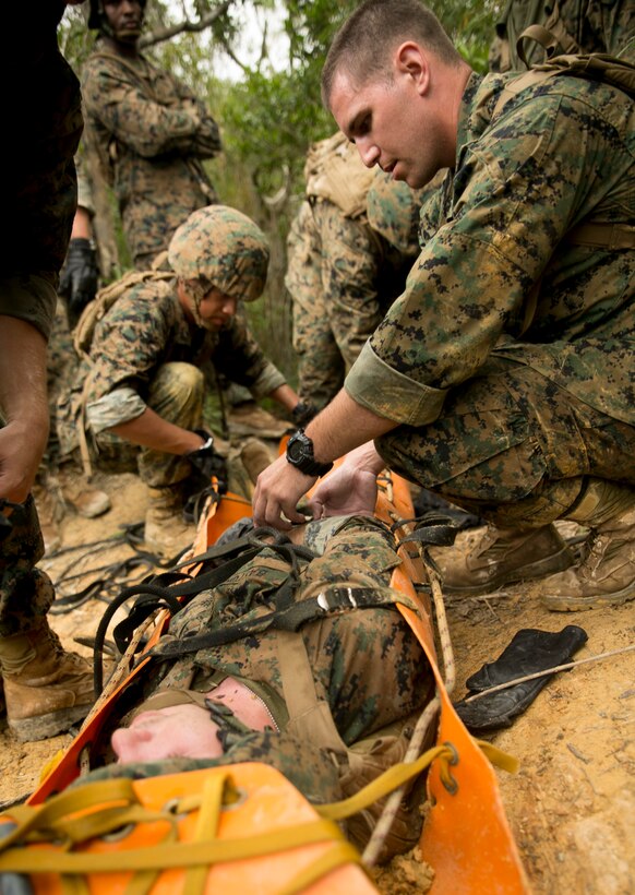 Petty Officer 2nd Class Joshua Scanlan, right, practices assessing a casualty during a practical application exercise that involves maneuvering a sked stretcher up a cliff during the Jungle Medicine Combat Course at the Jungle Warfare Training Center on Camp Gonsalves. During the course, the corpsmen learned practical techniques that they could apply when operating in a jungle environment. Scallan is an American Samoa native and corpsman with 3rd Dental Battalion, 3rd Marine Logistics Group, III Marine Expeditionary Force. (U.S. Marine Corps photo by Lance Cpl. Brittany A. James/released)