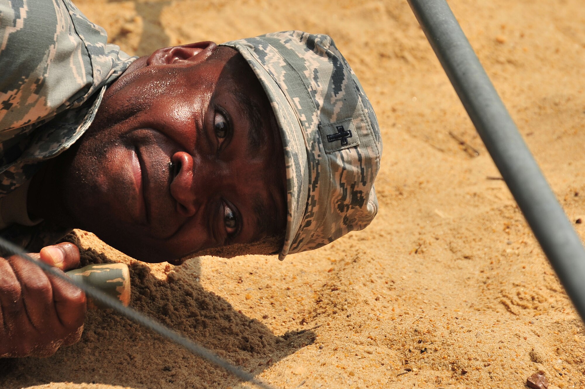 MAXWELL AIR FORCE BASE, Ala. -- A Commissioned Officer Training School student low-crawls while pulling a gurney under simulated fire at an Officer Training School exercise complex here, July 24, 2014. Commissioned medical, legal and chaplain officers must go through COT to receive military leadership training. This obstacle was a part of a deployment exercise, which tests leadership decision-making as well as contingency operations knowledge. (U.S. Air Force photo by Staff Sgt. Natasha Stannard)