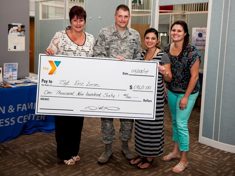 From left, Stacey Pennington, Santa Maria Valley Young Men’s Christian Association associate director, Tech Sgt. Eric Liese, 30th Space Communication Squadron non-commissioned officer in charge of executive communications, Krista Delia, SMV YMCA youth and volunteer coordinator, and Nadia Frakes, SMV YMCA child care director, pose for a photo during the check presentation to Liese July 28, 2014, Vandenberg Air Force Base, Calif.  The SMV YMCA runs a firework booth yearly to raise money for community support programs, and this year decided to donate eight percent of the proceeds to a local military support group. (U.S. Air Force Photo by Airman 1st Class Yvonne Morales/ Released)
