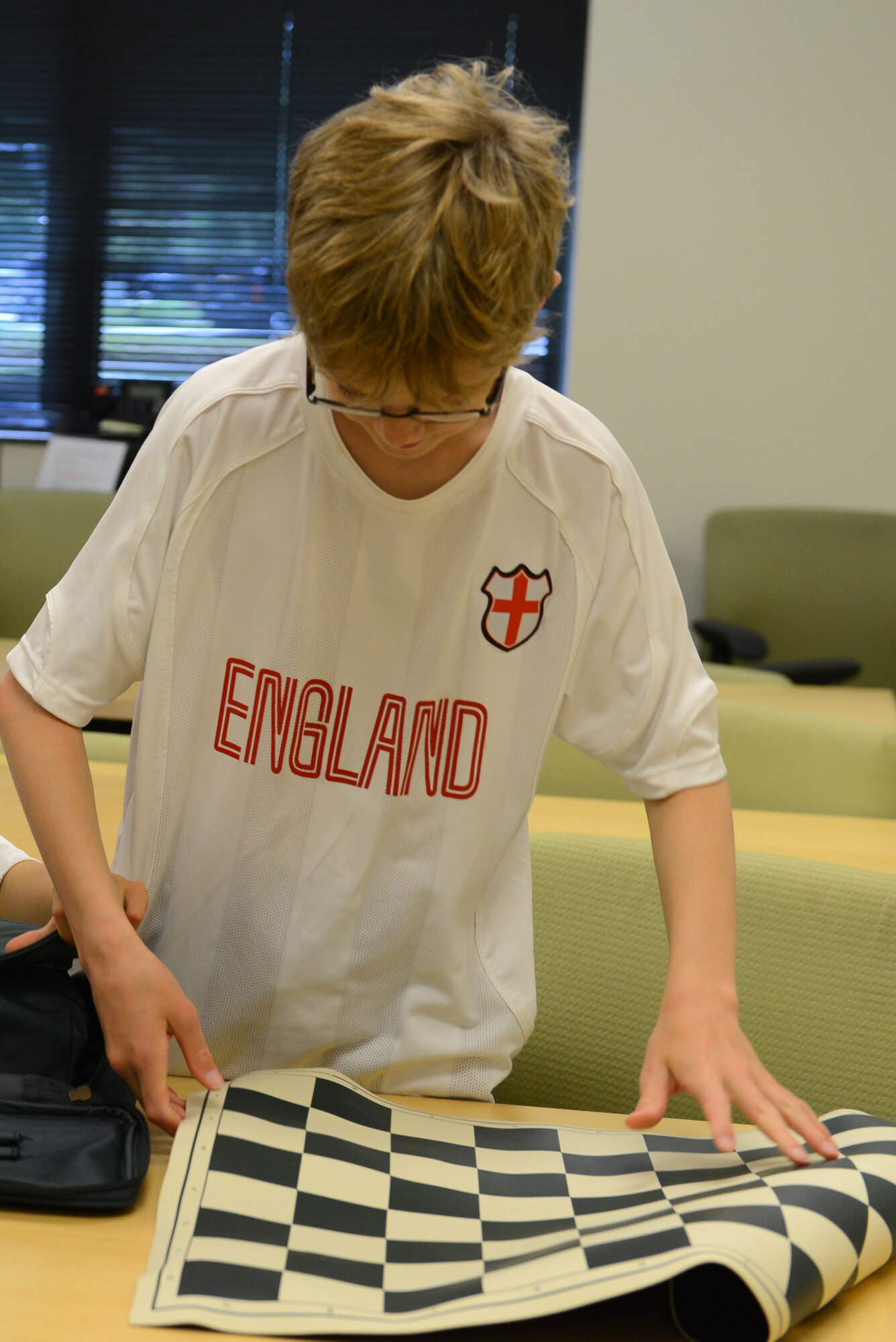 Caleb Hammon, 11-year-old son of U.S Air Force Lt. Col. Troy Hammon, U.S. Air Forces Central chief of contract and fiscal law, sets up the chess board for the chess club at Shaw Air Force Base, S.C., July 22, 2014. The club meets at the McElveen Resource Center every Tuesday from 4-6 p.m. (U.S. Air Force photo by Airman 1st Class Diana M. Cossaboom/Released)