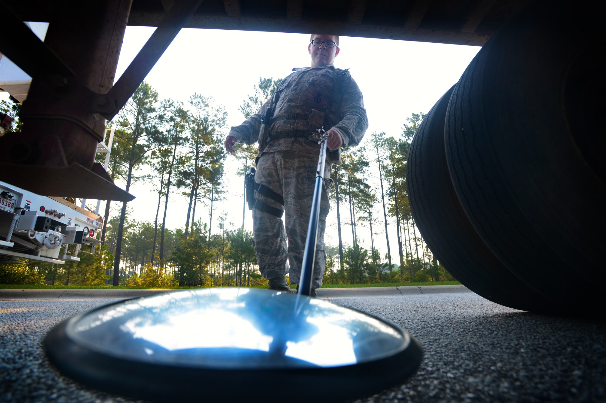 U.S. Air Force Senior Airman Jeremy Walker, 20th Security Forces Squadron installation entry control journeyman, uses an inspection mirror at the commercial vehicle inspection area at Shaw Air Force Base, S.C., July 24, 2014. During each vehicle inspection, the mirror is used to check under vehicles for drugs, alcohol, explosives and weapons. (U.S. Air Force photo by Airman 1st Class Jensen Stidham/Released) 