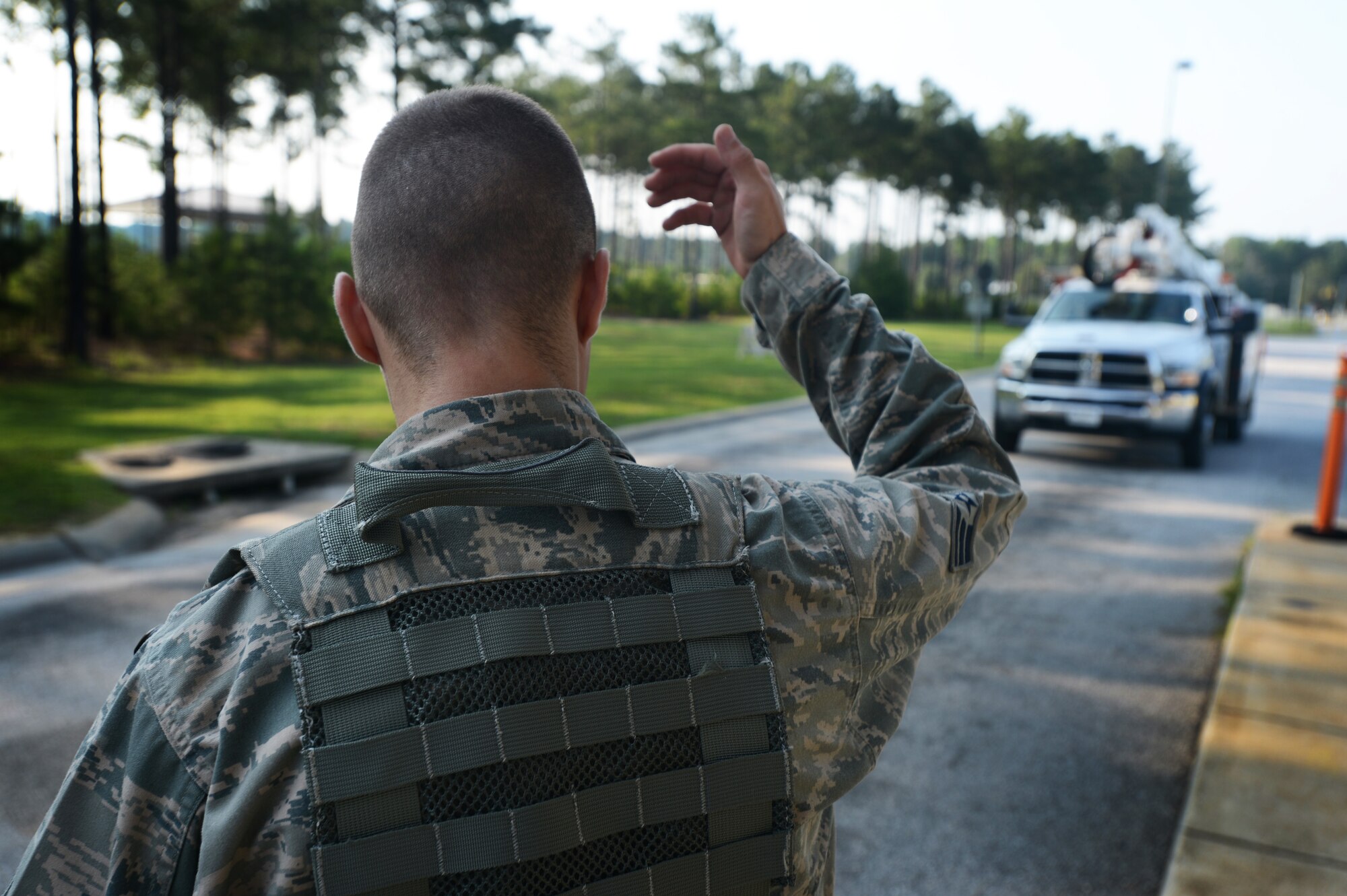 U.S. Air Force Senior Airman Ilya Makarenko, 20th Security Forces Squadron installation entry control journeyman, waves-on a vehicle at the commercial vehicle inspection area at Shaw Air Force Base, S.C., July 24, 2014. Vehicles must wait for approval, upon arrival, before entering the inspection point. (U.S. Air Force photo by Airman 1st Class Jensen Stidham/Releaesed)