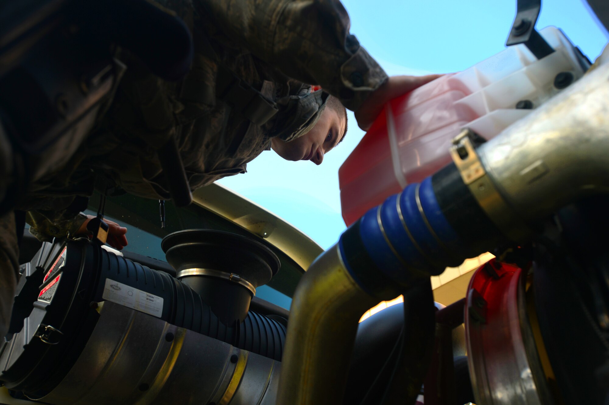 U.S. Air Force Senior Airman Ilya Makarenko, 20th Security Forces Squadron installation entry control journeyman, inspects a semi-truck engine at the commercial vehicle inspection area at Shaw Air Force Base, S.C., July 24, 2014. During their 100 percent vehicle checks, the Airmen inspect every compartment of a vehicle; to include the undercarriage and inside the cabins. (U.S. Air Force photo by Airman 1st Class Jensen Stidham/Released)