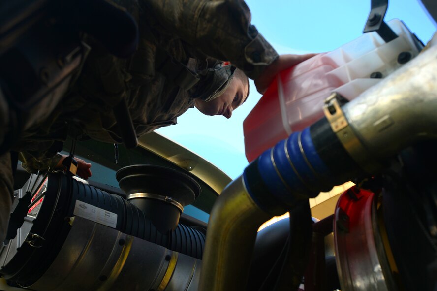 U.S. Air Force Senior Airman Ilya Makarenko, 20th Security Forces Squadron installation entry control journeyman, inspects a semi-truck engine at the commercial vehicle inspection area at Shaw Air Force Base, S.C., July 24, 2014. During their 100 percent vehicle checks, the Airmen inspect every compartment of a vehicle; to include the undercarriage and inside the cabins. (U.S. Air Force photo by Airman 1st Class Jensen Stidham/Released)