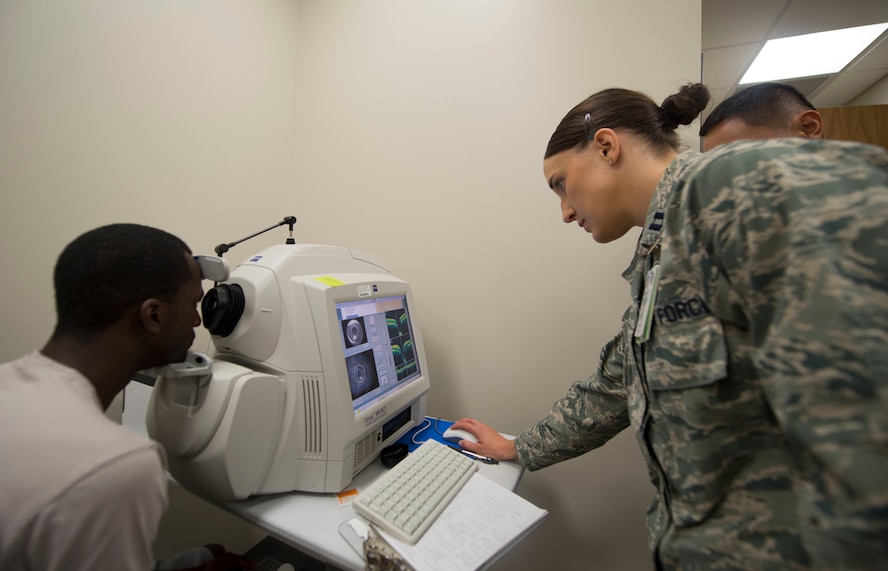 U.S. Air Force Capt. (Dr.) Kaylaen Dittmer, 23d Medical Group optometry specialist, analyzes the eyes of Senior  Airman Nelson Rolle, 23d Medical Group dental assistant journeyman,  at the optometry clinic at Moody Air Force Base, Ga., July 25, 2014. Dittmer uses the photos to determine health issues, such as glaucoma. (U.S. Air Force photo by Airman 1st Class  Dillian Bamman /Released)