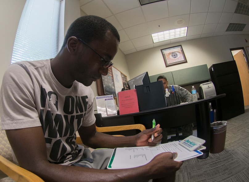 U.S. Air Force Senior Airman Nelson Rolle,  23d Medical Group dental assistant journeyman, fills out an appointment sign-in sheet at the optometry clinic at Moody Air Force Base, Ga., July 25, 2014. The clinic requires patients with prescriptions to complete yearly check-ups for eyesight and health examinations. (U.S. Air Force photo by Airman 1st Class  Dillian Bamman /Released)