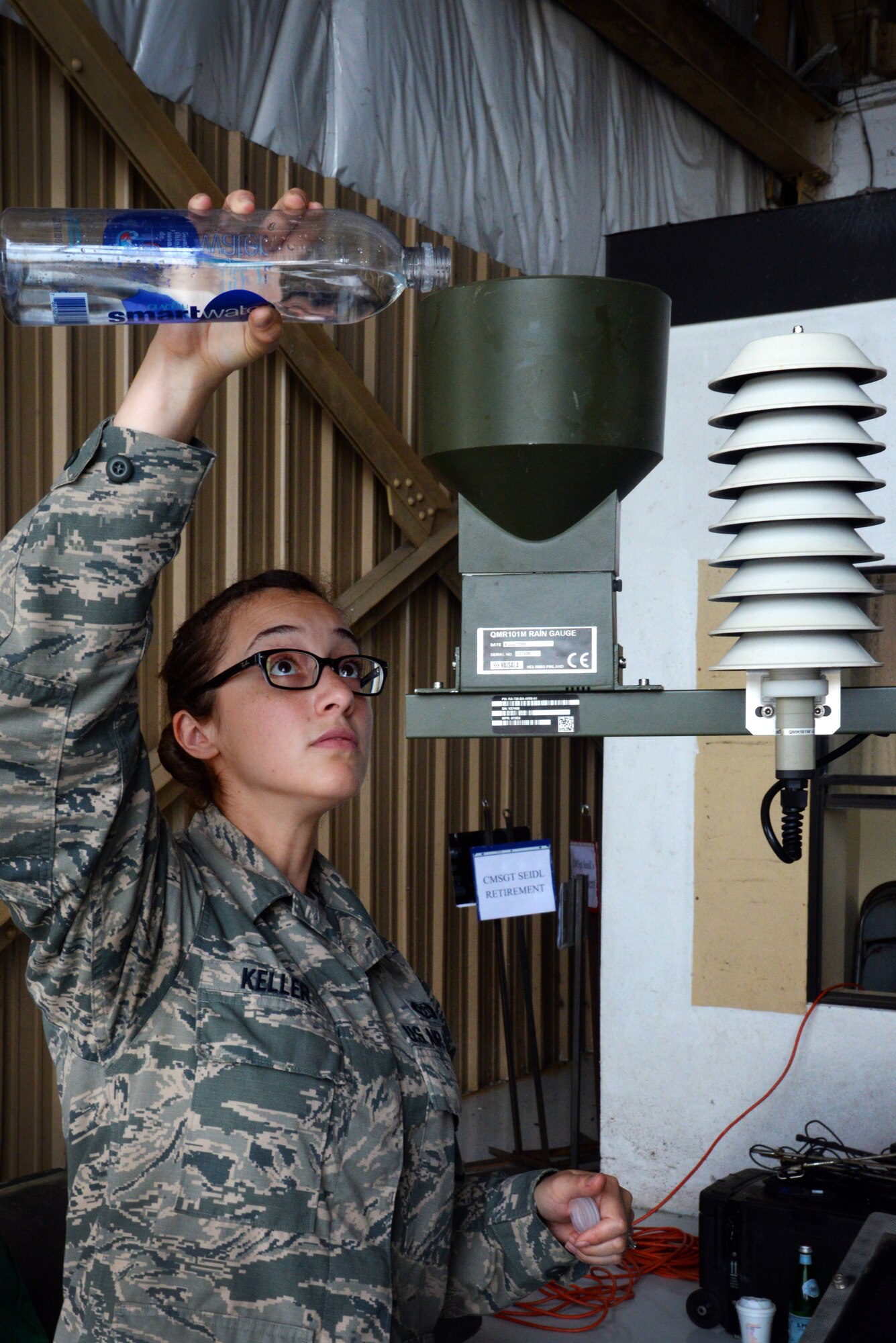 U.S. Air Force Senior Airman Starr Keller, 20th Operational Support Squadron weather forecaster, pours water into a Tactical Meteorological Observance System-53 rain gauge during the 20th Operations Group open house at Shaw Air Force Base, S.C., July 28, 2014. The TMOS-53, hooked up to a computer to show weather statistics, is used by Airmen across the Air Force to assist in forecasting weather for operations. (U.S. Air Force photo by Airman 1st Class Jonathan Bass/Released)