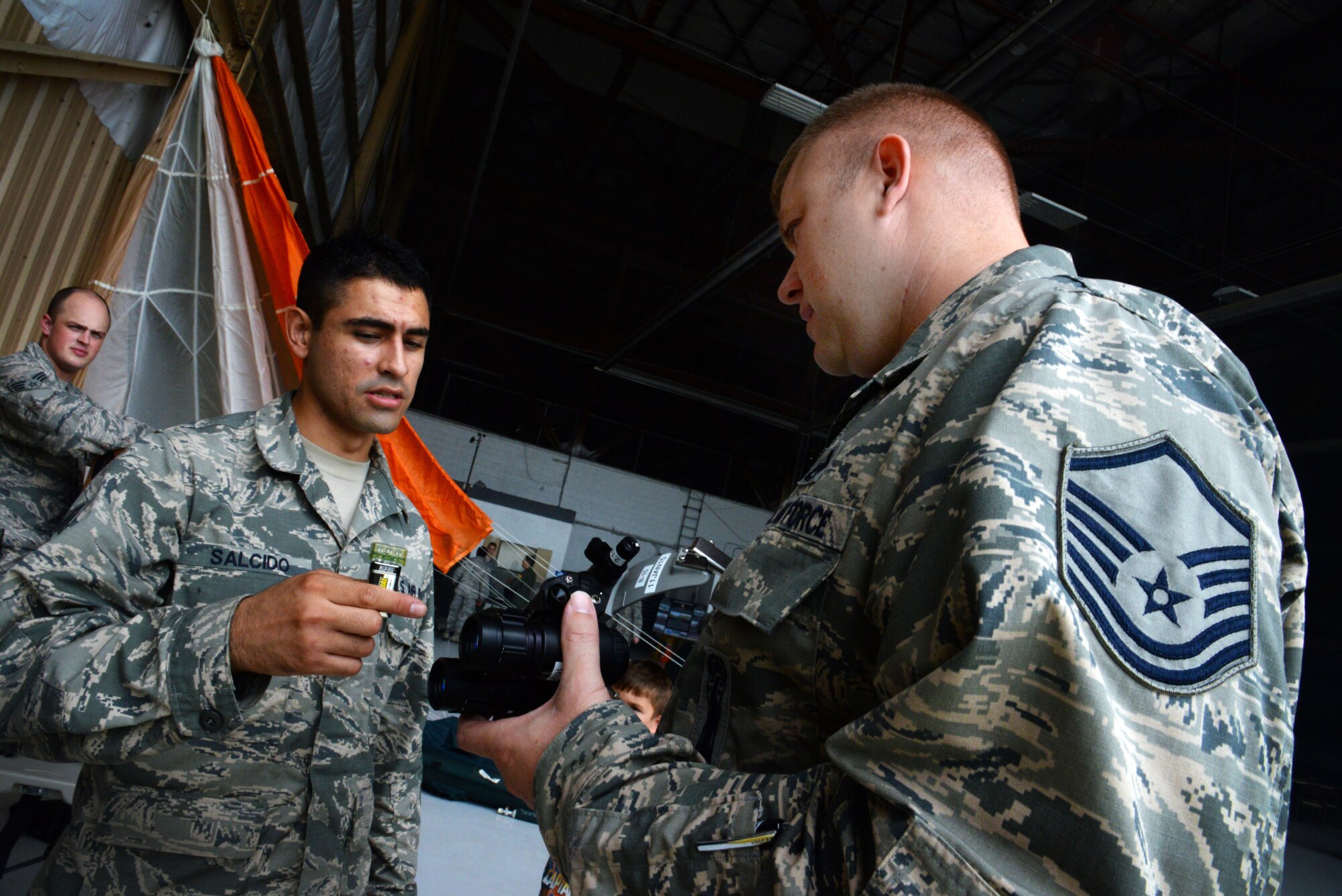 U.S. Air Force Senior Airman Jerry Salcido, 20th Operational Support Squadron aircrew flight equipment journeyman assigned to the 77th Fighter Squadron, teaches Master Sgt. Daniel Marcoux, 20th OSS first sergeant, about a set of night vision goggles during the 20th Operations Group open house at Shaw Air Force Base, S.C., July 28, 2014. The open house showed families and other service members the 20th OG, to provide aircraft and Airmen for conventional and anti-radiation suppression of enemy air defenses, strategic attack, counter air, air interdiction, joint maritime operations and combat search-and-rescue missions. (U.S. Air Force photo by Airman 1st Class Jonathan Bass/Released)
