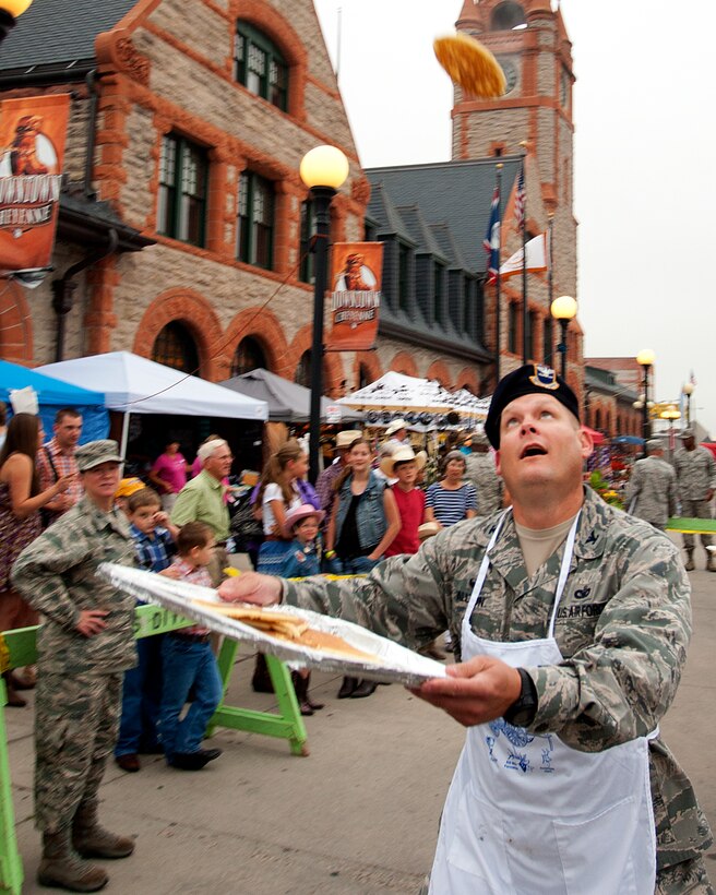 Col. Craig Allton, 90th Security Forces Group commander, catches a pancake in Depot Plaza, Cheyenne, Wyo., July 23, 2014 as Col. Tracey Hayes, 90th Missile Wing commander, watches his technique. Free pancake breakfasts, feeding thousands of visitors, are a tradition during the annual Cheyenne Frontier Day festivities, with local organizations volunteering to handle the spatulas and tossing the flapjacks to other volunteers waiting to catch them. (U.S. Air Force photo by R.J. Oriez)