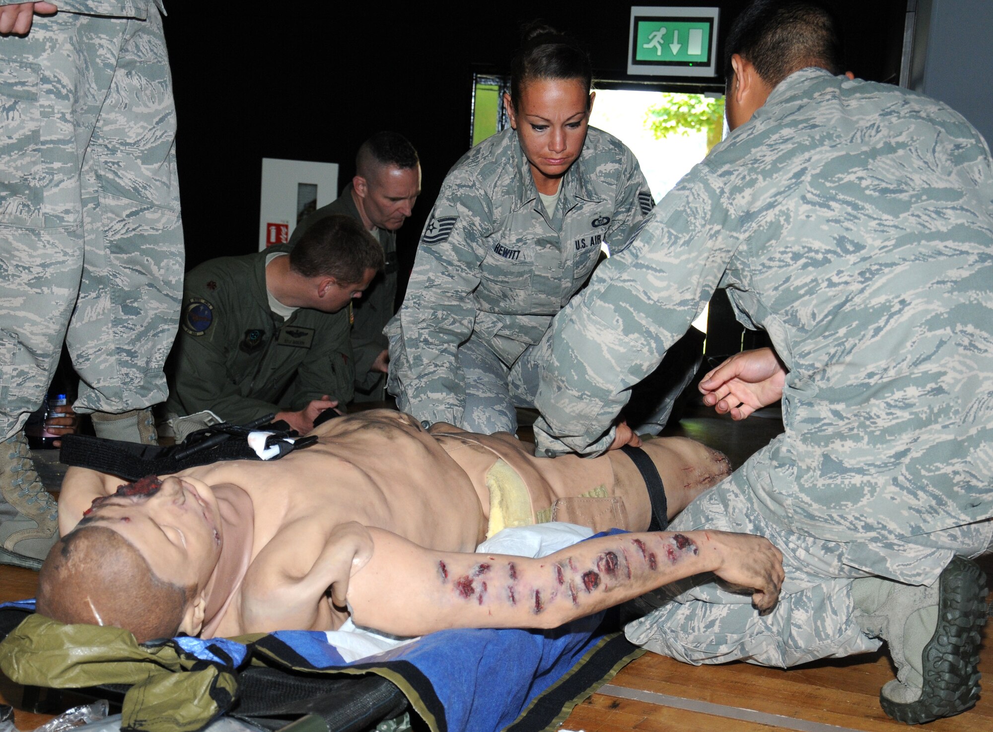 U.S. Air Force Tech. Sgt. Jennifer Hewitt, center, 352nd Special Operations Group aviation resource manager from Dayton, Ohio, applies a tourniquet to a mannequin with the help of a trainer, U.S. Air Force Tech. Sgt. Eduardo Clemente, left, 352nd Special Operations Support Squadron independent duty medical technician from Dothan, Ala., during self-aid buddy care training July 24, 2014, on RAF Mildenhall, England. Members took part in SABC training to improve and test their life-saving skills. Applying a tourniquet can help stop critical bleeding until medical help arrives. (U.S. Air Force photo/Gina Randall/Released)