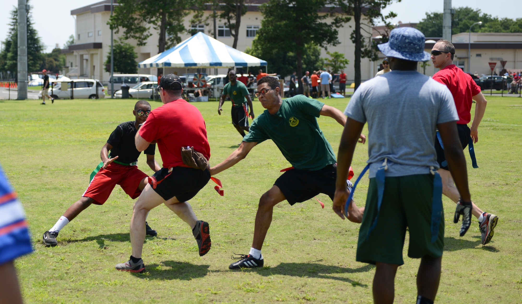 YOKOTA AIR BASE, Japan -- An Airman playing flag football attempts to run through members of the 374th Civil Engineer Squadron defense during Airman Appreciation Day at Yokota Air Base, Japan, July 25, 2014. Flag football was just one event that counted toward an overall score for participating squadrons; the winner takes a trophy back to their squadron to display for the following year. (U.S. Air Force photo by Staff Sgt. Cody H. Ramirez/Released)

