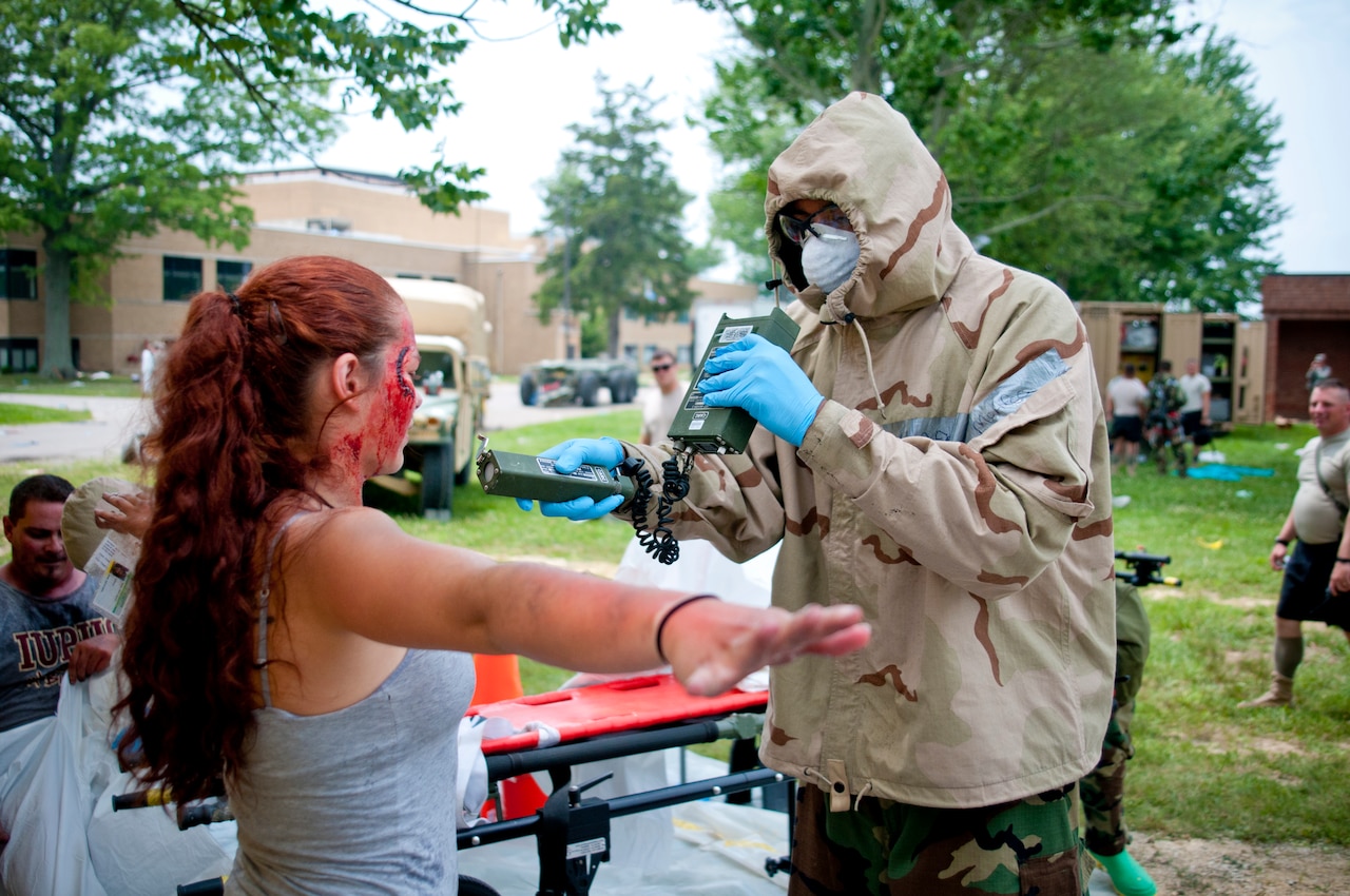 Army Spc. Tevin McAfee, from the 60th Engineer Company, 11th Engineer Battalion, Fort Benning, Ga., uses a radiation detector on Marley Bruce, a role player from Madison, Ind., after she exits a decontamination tent, July 23, 2014, as part of Vibrant Response ’14 at Camp Atterbury, Ind. U.S. Army photo by Staff Sgt. Timothy Koster