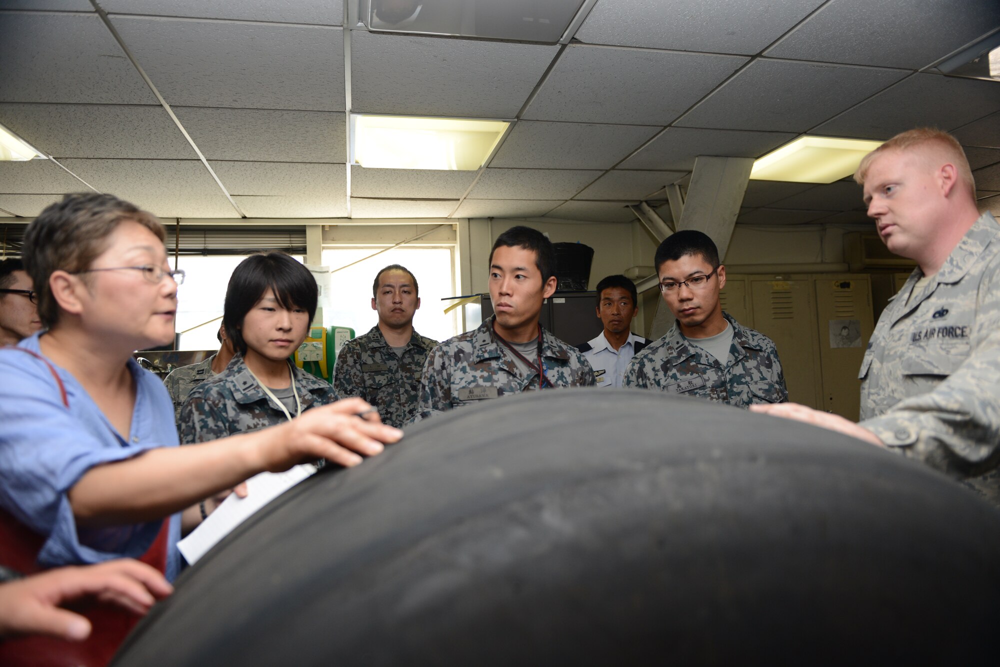 YOKOTA AIR BASE, Japan -- Mitsuru Takahashi, 374th Airlift Wing Public Affairs chief of community relations, explains tire maintenance to a group of Japan Air Self-Defense Forces maintenance officers at Yokota Air Base, Japan, July 29, 2014. Takahashi assisted communication between the JASDF officers and members of the 374th Airlift Wing as they discussed specifics of Yokota's maintenance operations. (U.S. Air Force photo by Staff Sgt. Cody H. Ramirez/Released)