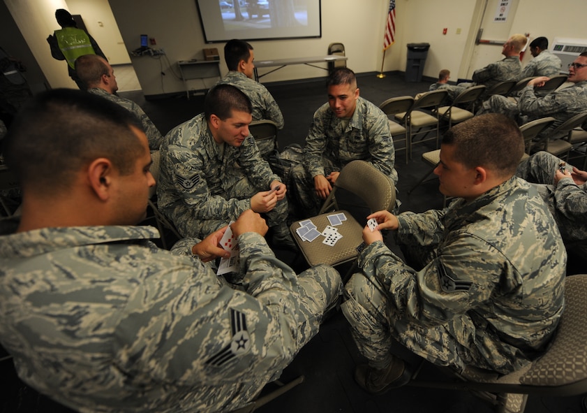 U.S. Air Force Airmen from the 9th Bomb Squadron and 7th Maintenance Group play cards in the Deployment Control Center at Dyess Air Force Base, Texas, July 29, 2014. Many Airmen brought items such as games and electronic devices to pass time while waiting to depart for Al Udeid Air Base, Qatar, where they will be supporting Operation Enduring Freedom. (U.S. Air Force photo by Airman 1st Class Alexander Guerrero/Released)