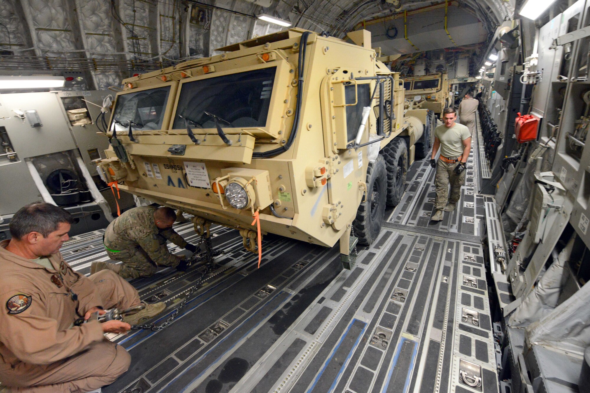 Master Sgt. John Sadorf, left, works with Airman 1st Class Alex Burgess as they tighten cables to secure the front end of a heavy expanded mobility tactical truck inside a C-17 Globemaster III aircraft on Bagram Airfield, Afghanistan, July 20, 2014. Sadorf, a loadmaster, is assigned to the 817th Airlift Squadron, and deployed from the 313th Airlift Squadron at Joint Base Lewis-McChord, Wash. (U.S. Air Force photo/Master Sgt. Cohen Young)