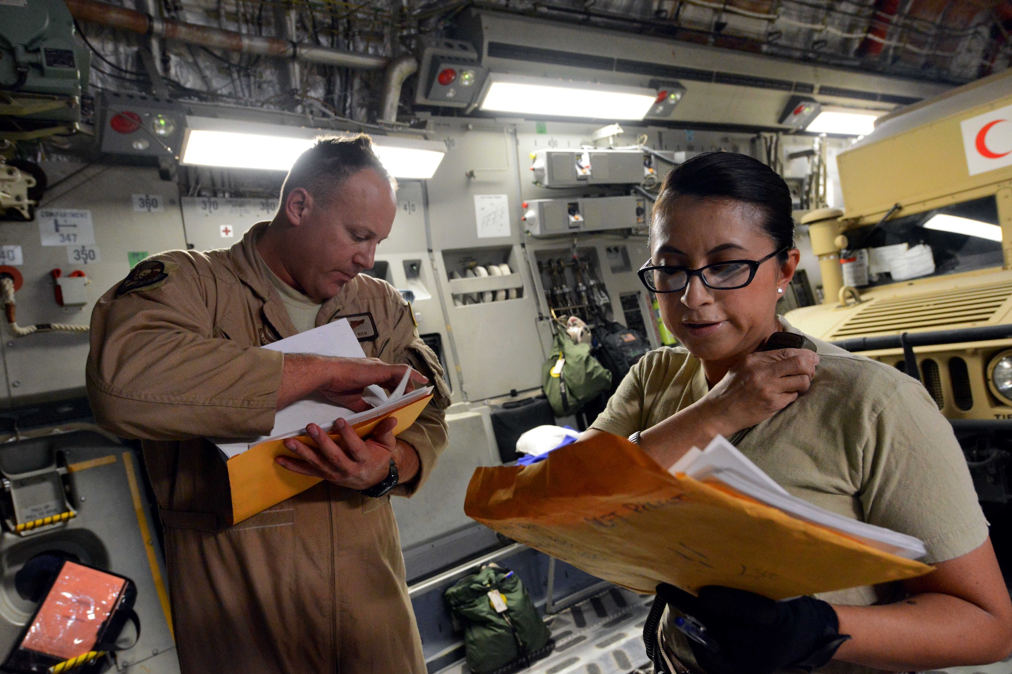 Tech. Sgt. Cory Rich, left, goes over the cargo records with Tech. Sgt. Norma Martinez as they verify the weight and the number of vehicles being offloaded and later loaded onto a C-17 Globemaster III aircraft after landing on Bagram Airfield, Afghanistan, July 20, 2014. Rich, a loadmaster, and Martinez, an information controller, are assigned to the 455th Expeditionary Aerial Port Squadron. Rich is deployed from the 8th Airlift Squadron at Joint Base Lewis-McChord, Wash., and Martinez is deployed from the 26th Aerial Port Squadron on Joint Base San Antonio, Texas. (U.S. Air Force photo/Master Sgt. Cohen Young)