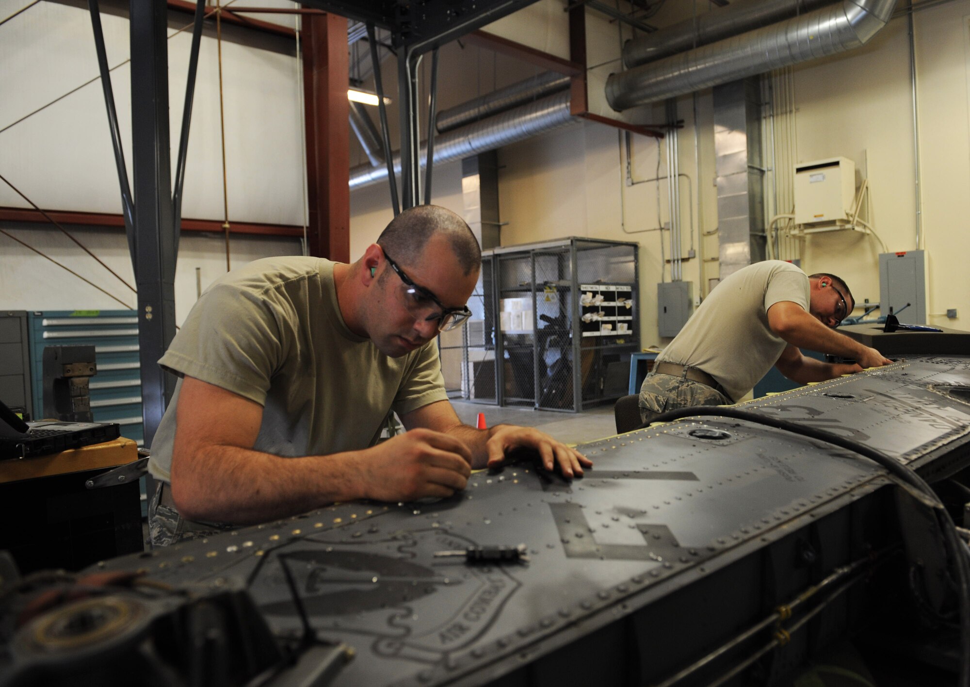 Senior Airman William Georgen (left), 823rd Maintenance Squadron aircraft structural mainframe journeyman, and Staff Sgt. Nate Mainville, 823rd MXS aircraft structural mainframe craftsman, replace the structural strap on the tail pylon of an HH-60G Pave Hawk during an accelerated inspection phase, July 25, 2014, at Nellis Air Force Base, Nev. Any manpower or materials needed to fix or replace any piece of equipment are readily available at the on-site sheet metal shop. Having the shop on site allows the squadron to set its own priorities as to what needs to be fixed first. (U.S. Air Force photo by Airman 1st Class Thomas Spangler)
