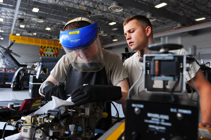 Senior Airman Ryan Wilkerson (right), 823rd Maintenance Squadron guidance and control specialist, supervises Airman 1st Class Joseph Stuart, 823rd MXS guidance and control specialist, as he makes adjustments on a piece of equipment for an HH-60G Pave Hawk during an accelerated inspection phase, July 25, 2014, at Nellis Air Force Base, Nev. The goal of the accelerated inspection phase is to reduce the amount of time the helicopter is out of commission from 45 calendar days to 17 calendar days. (U.S. Air Force photo by Airman 1st Class Thomas Spangler)