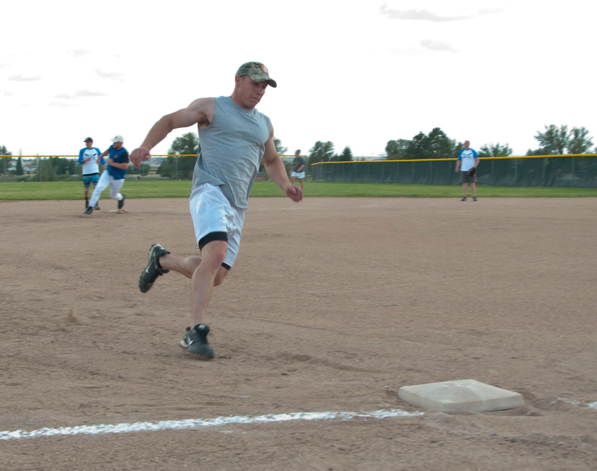 Michael Harris, 90th Munitions Squadron, sprints to round third and head for home during the intramural softball game between the 90th MUNS and the 90th Missile Security Forces Squadron July 28, 2014, on one of the F.E. Warren Air Force Base, Wyo., softball fields. Harris made it home, and Jacob Burns (seen in the background), who made the hit for the play, made it to third. (U.S. Air Force photo by Airman 1st Class Jason Wiese)