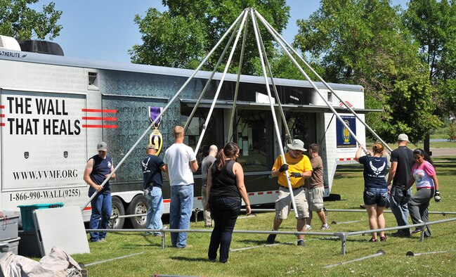Volunteers raise supports for a tent connected to the Vietnam Veterans Memorial mobile museum July 23 at Elk’s Riverside Park in Great Falls, Mont. The exhibit is built into the exterior of the trailer that transports The Wall That Heals, and tells the story of the Vietnam War and the memorial. (U.S Air Force photo/John Turner)