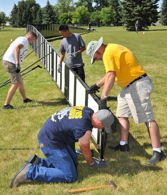 Airman Adam Kresge (left), Airman 1st Class Bryson Baptista (center) and Airman 1st Class Clayton Reeb (foreground), all from the 819th RED HORSE Squadron, assist Bob Dobek (right), site supervisor of The Wall That Heals, erect the half-scale replica of the Vietnam Veterans Memorial Wall on July 23 at Elk’s Riverside Park. The traveling exhibit allows veterans and families to find solace at the memorial while in the comfort of their own communities. It was in Great Falls, Mont., through July 27. (U.S. Air Force photo/John Turner)