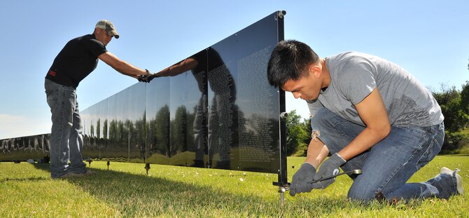 Senior Airman Anthony Bumbulsky and Airman 1st Class Brian Kim, both 819th RED HORSE Squadron structural apprentices, level a panel as they assemble The Wall That Heals on July 23 at Elks Riverside Park in Great Falls, Mont. The 250-foot wide display is a half-scale replica of the Vietnam Veterans Memorial Wall in Washington, D.C. Constructed from aluminum, the 24 panels list more than 58,200 names of American service members killed or missing during the Vietnam War. (U.S. Air Force photo/John Turner)