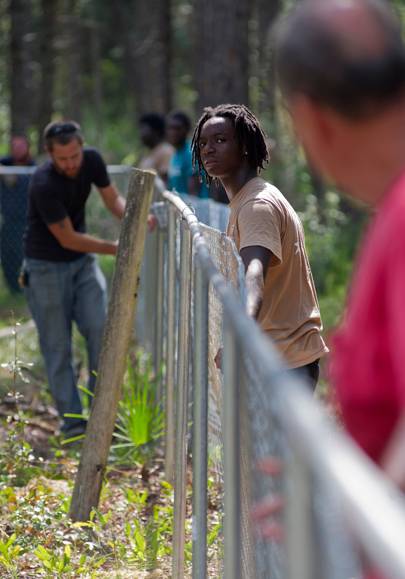 Markeis Goodman, Bay High School student, holds a fence while it is tightened July 28, at a Tyndall cemetery. He along with three other students from Bay District Schools have constructed around 1,100 feet of fence around Tyndall’s cemeteries to protect and preserve the grave sites on base. (U.S. Air Force photo by Airman 1st Class Alex Echols)