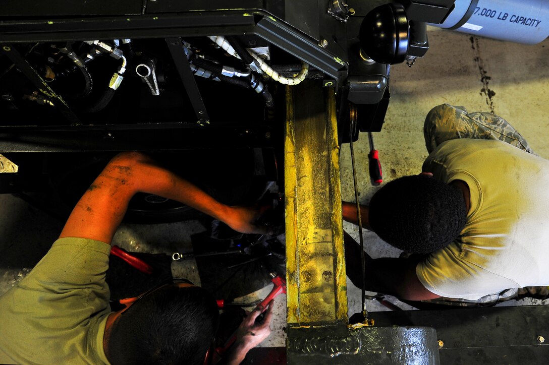 Senior Airman Timothy Davis and Airman 1st Class Cody Crawford, 5th Maintenance Squadron aerospace ground equipment apprentices, provide maintenance on a munitions hauling unit at Minot Air Force Base, N.D., July 23, 2014. AGE Airmen repair and maintain the ground equipment used to keep B-52H Stratofortresses prepared for flight. (U.S. Air Force photo/Senior Airman Brittany Y. Bateman)
