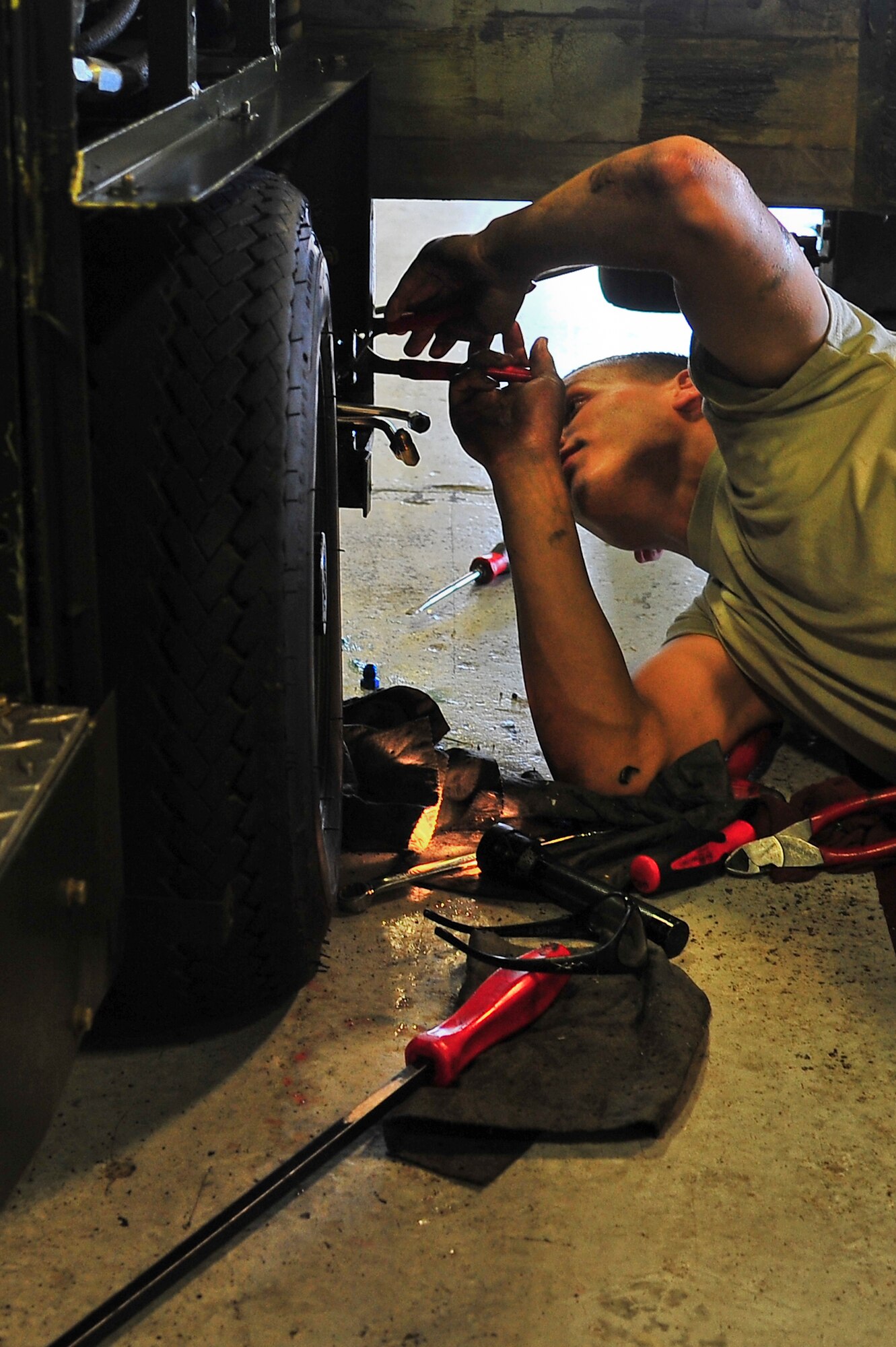 Airman 1st Class Cody Crawford, 5th Maintenance Squadron aerospace ground equipment apprentice, provides maintenance on a munitions hauling unit on Minot Air Force Base, N.D., July 23, 2014. AGE Airmen maintain the equipment that supplies electricity, hydraulic pressure and air pressure to planes receiving maintenance on the flight line. (U.S. Air Force photo/Senior Airman Brittany Y. Bateman)